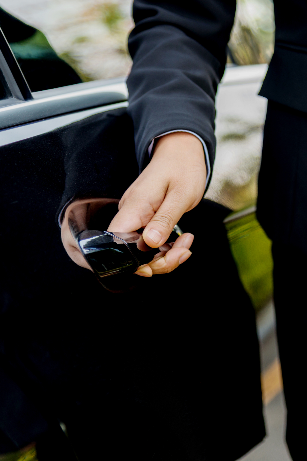 Chauffeur opening the door of a black executive car