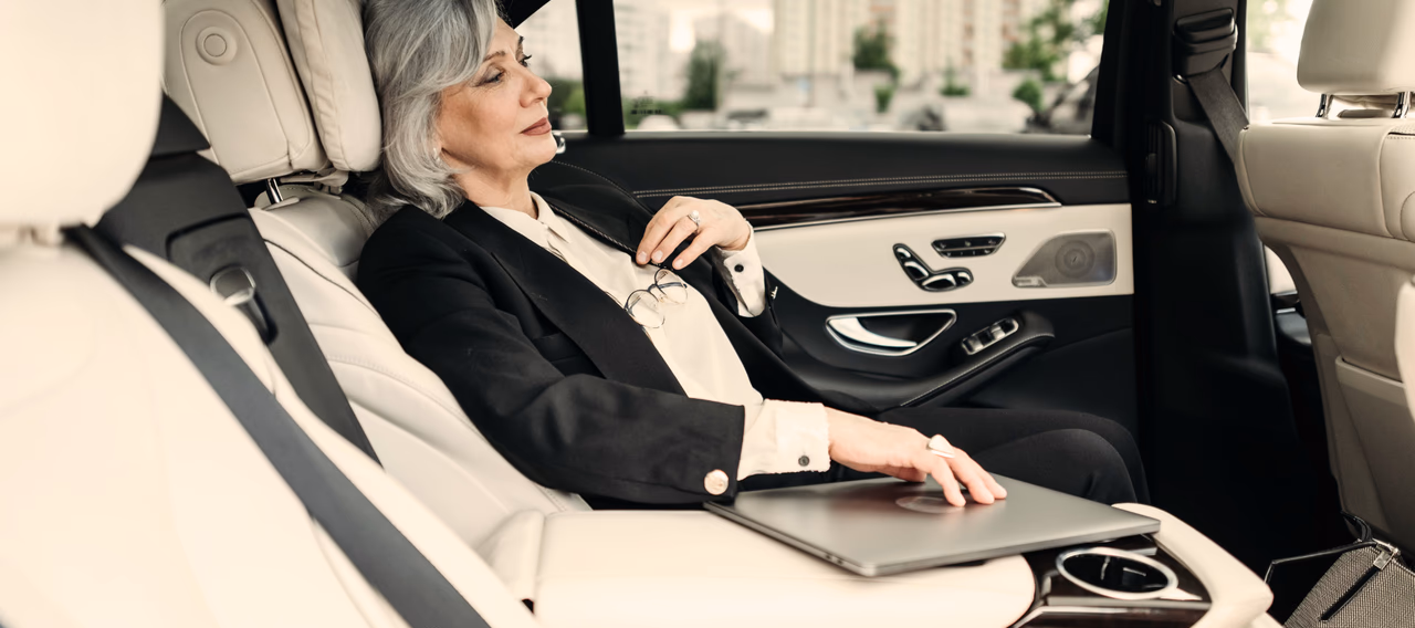 Executive working on a laptop in the back of a luxury chauffeur-driven car