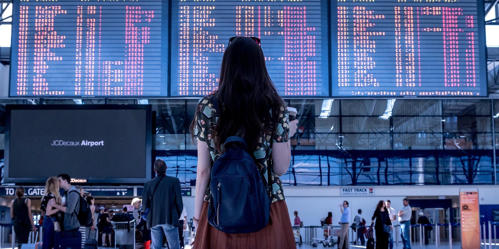 Solo traveller checking flight departure boards in a busy airport terminal