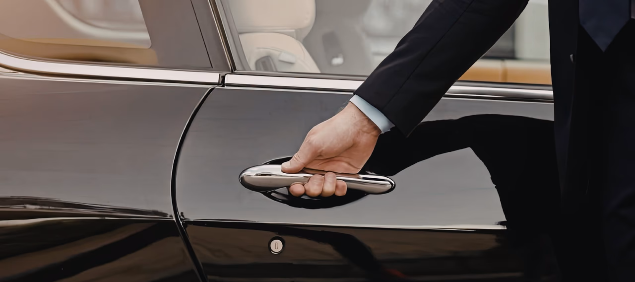Chauffeur hand opening a door of a luxury car
