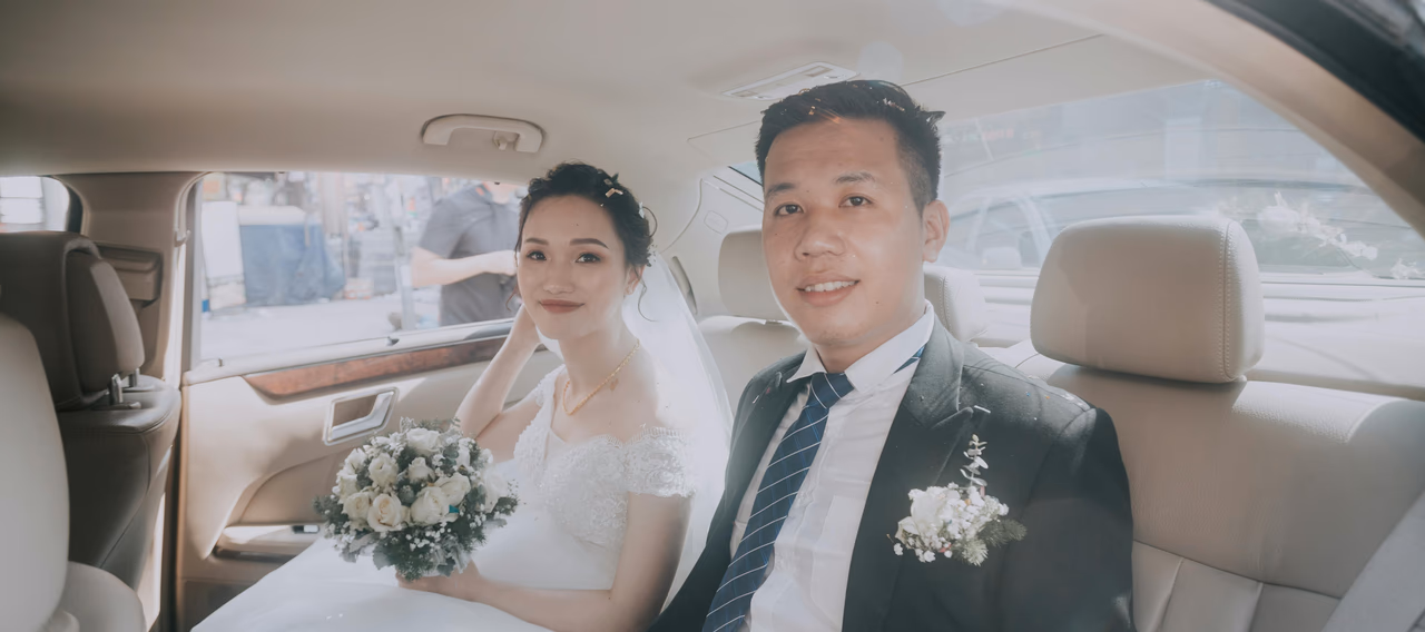 Bride and groom seated in the back of a luxury chauffeur-driven wedding car